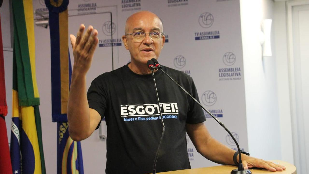 Um homem falando em uma tribuna. Atr&aacute;s dele h&aacute; uma bandeira do Brasil