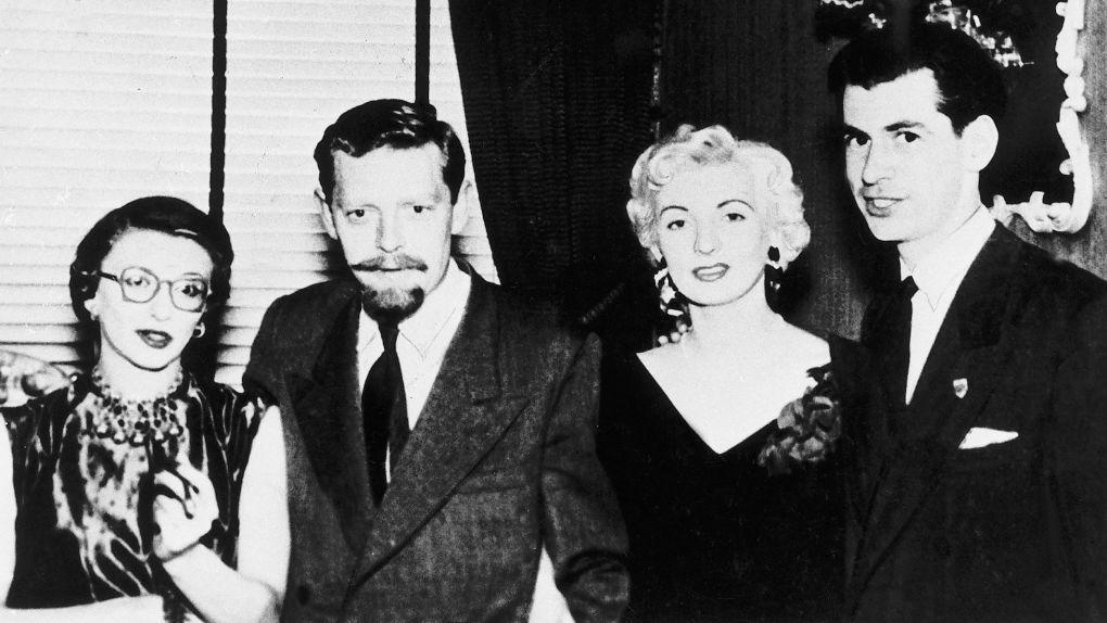 Ellis y Blakely vestidos y arreglados elegantemente junto a un hombre con barba y bigote, y una mujer de pelo oscuro, con gafas.
