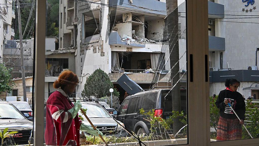 عاملتان تنظفان الزجاج المحطم إثر غارة جوية استهدفت فندقا في بيروت