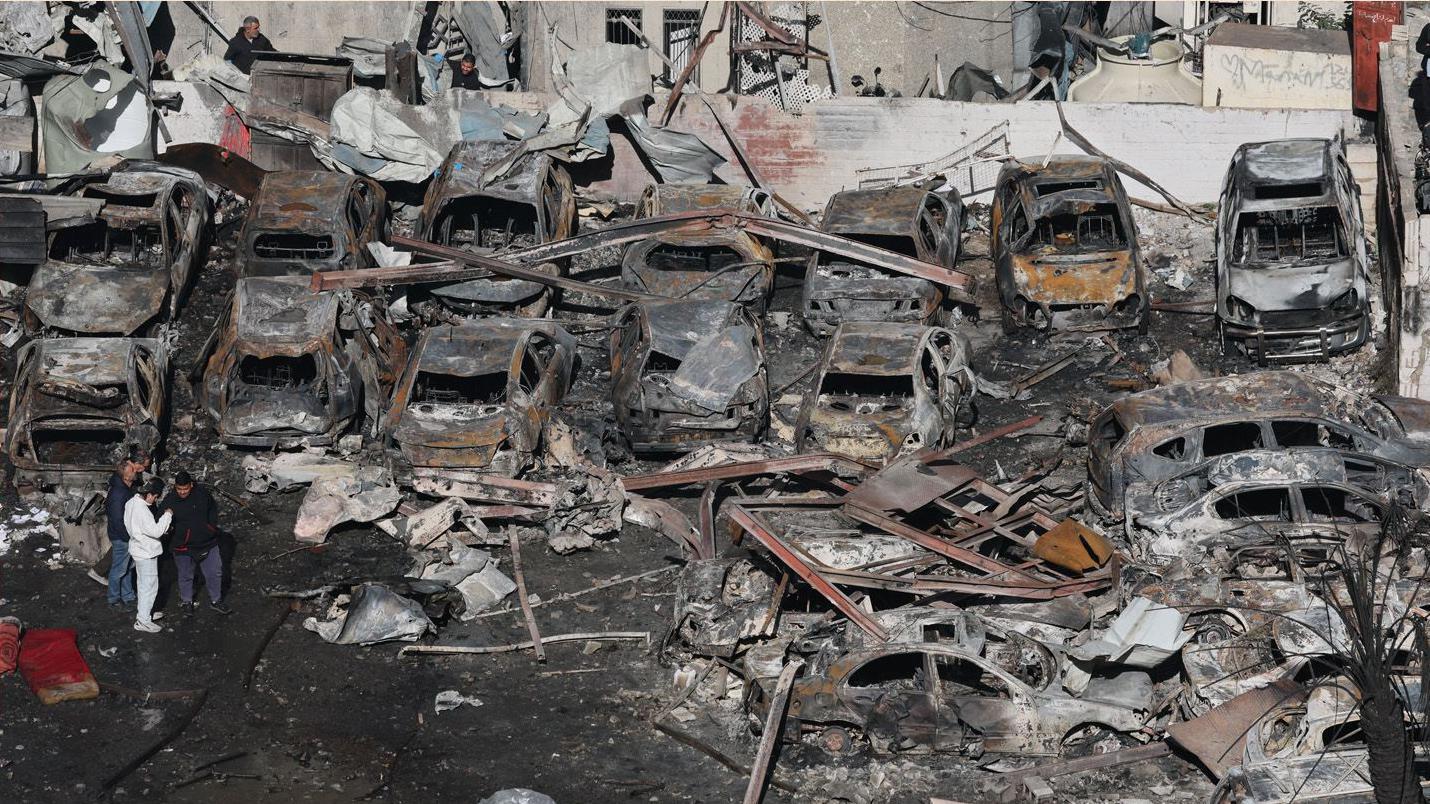 在貝魯特濱海大道（Corniche el-Mazraa）街區，人們走過以色列空襲摧毀的汽車和建築物廢墟。