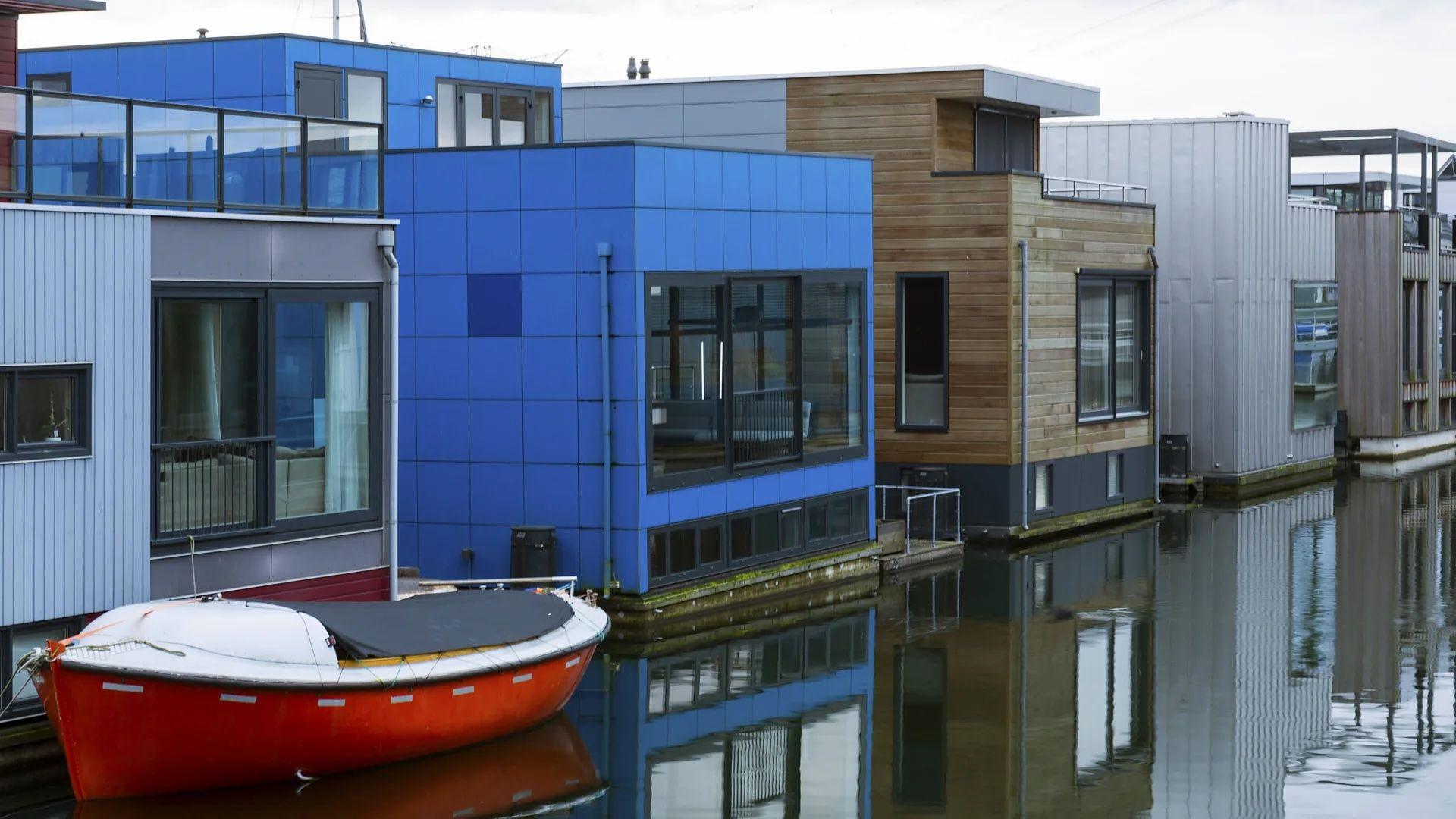 Una serie de casas flotantes de distintos colores, con un bote al frente
