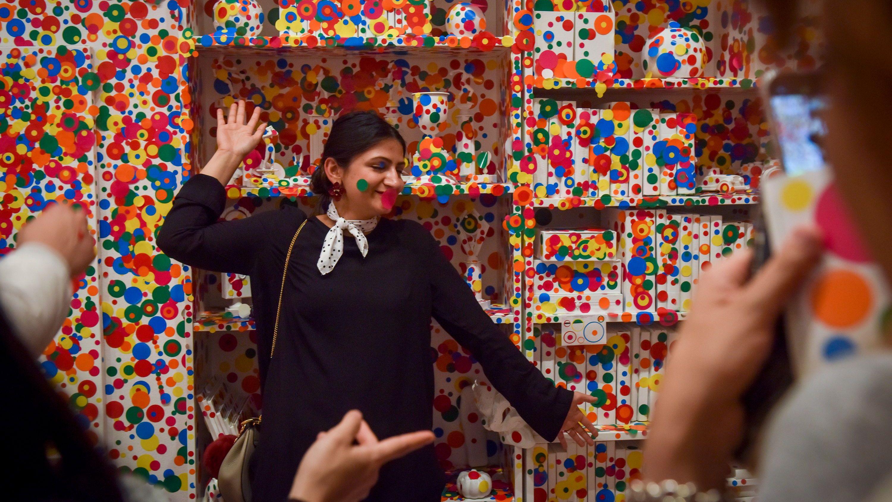 Una visitante de la galería posa frente a una pared cubierta de puntos multicolores en el último día de la exposición Yayoi Kusama: Infinity Mirrors en el Museo Hirshhorn del Instituto Smithsonian, el domingo 14 de mayo de 2017.