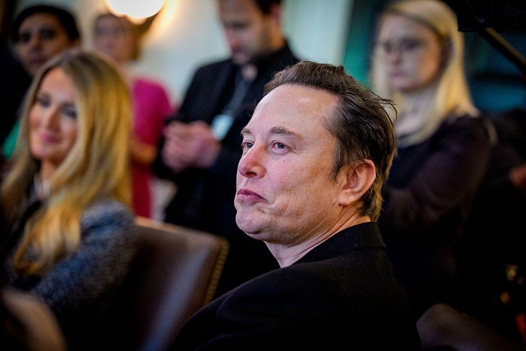 Elon Musk sentado em um auditório