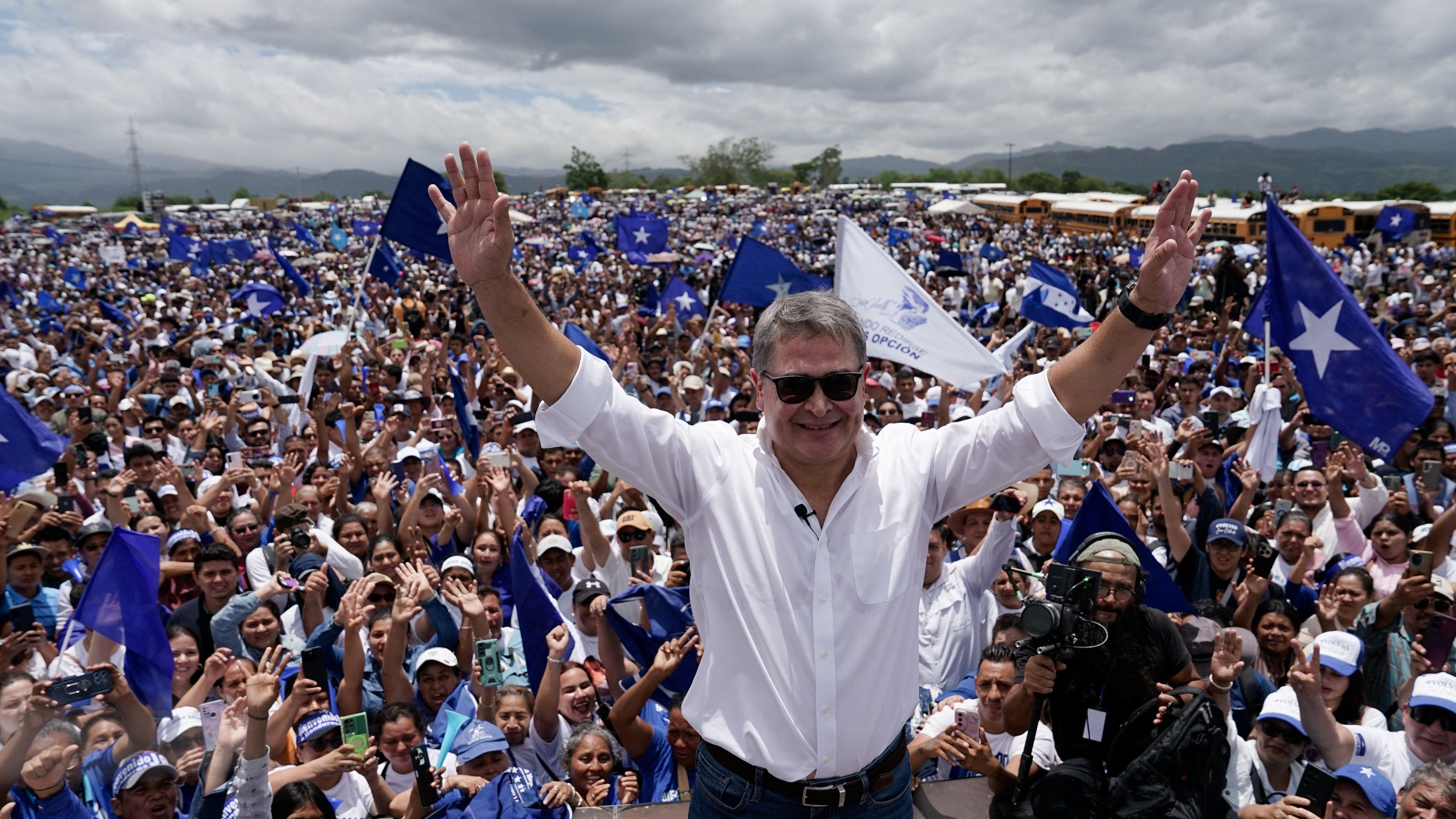 Hernández saluda a sus simpatizantes rodeado de banderas azules del Partido Nacional.