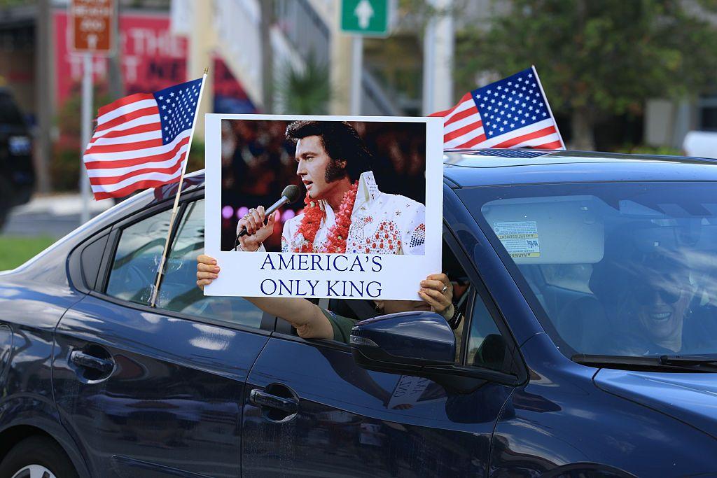 Personas en un carro con un letrero en el que dicen que Elvis es el único rey de EE.UU.