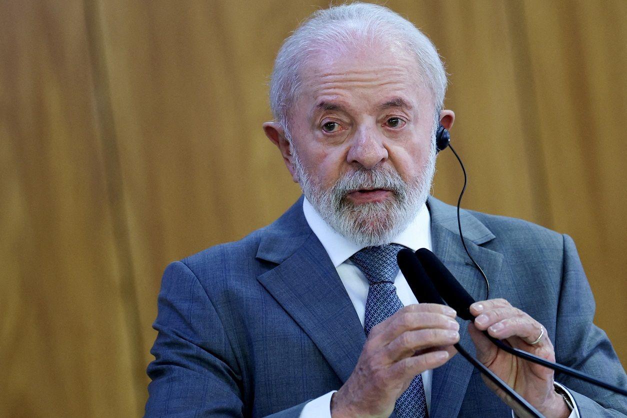 Lula olhando compenetrado para algo, usando fone para tradução e mexendo em microfone