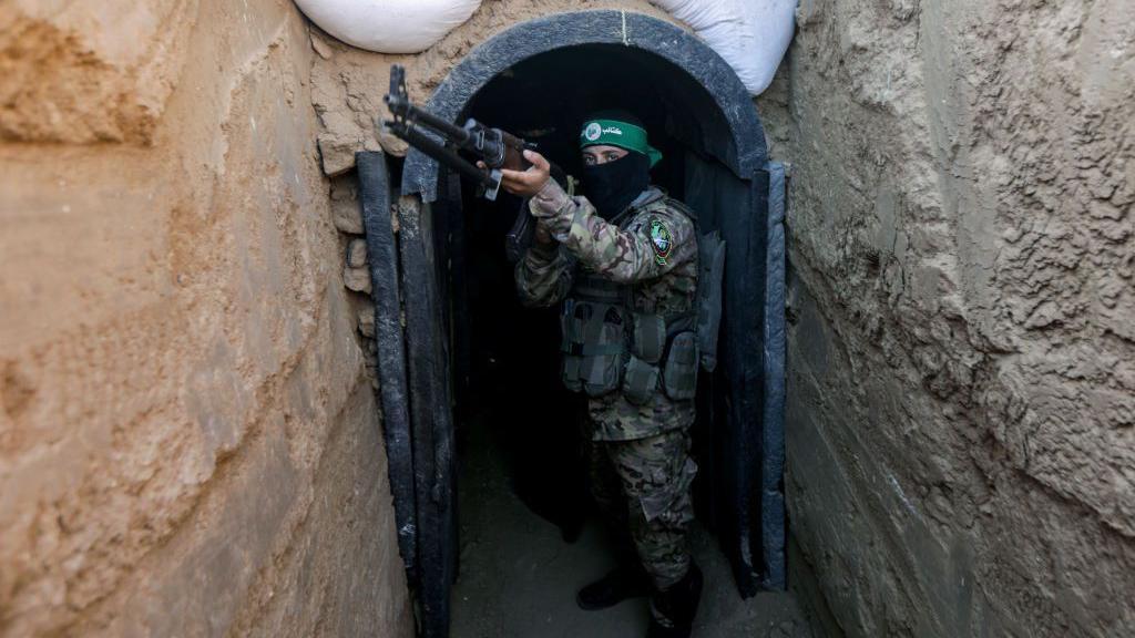 Combatente do Hamas segura uma espingarda na entrada de um t&uacute;nel