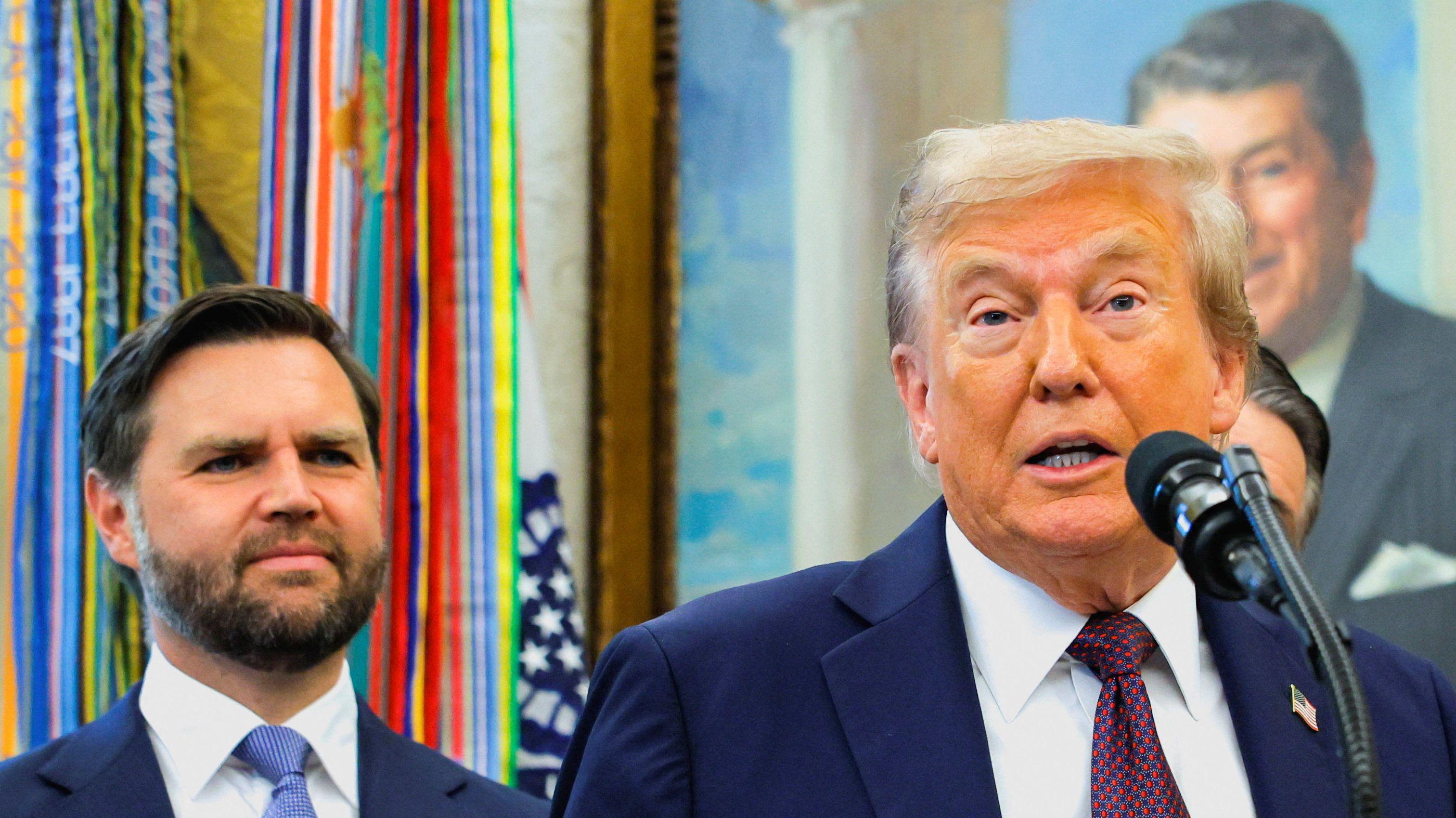 O vice-presidente americano J.D. Vance ouve o presidente Donald Trump. Ao fundo, um retrato do ex-presidente Ronald Reagan