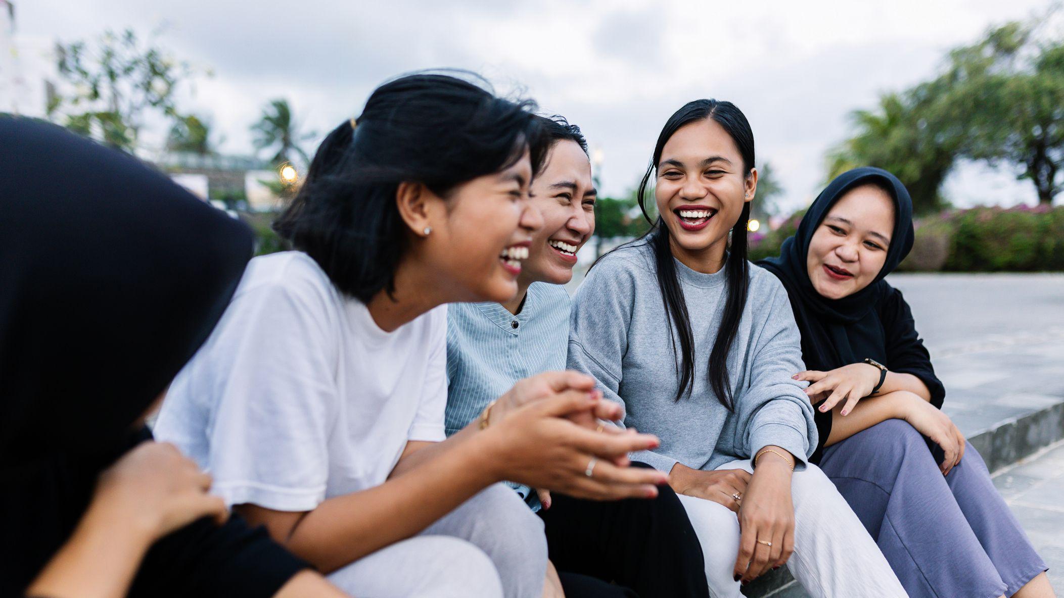 다섯 명의 십대 소녀들이 함께 앉아 웃고 있다.