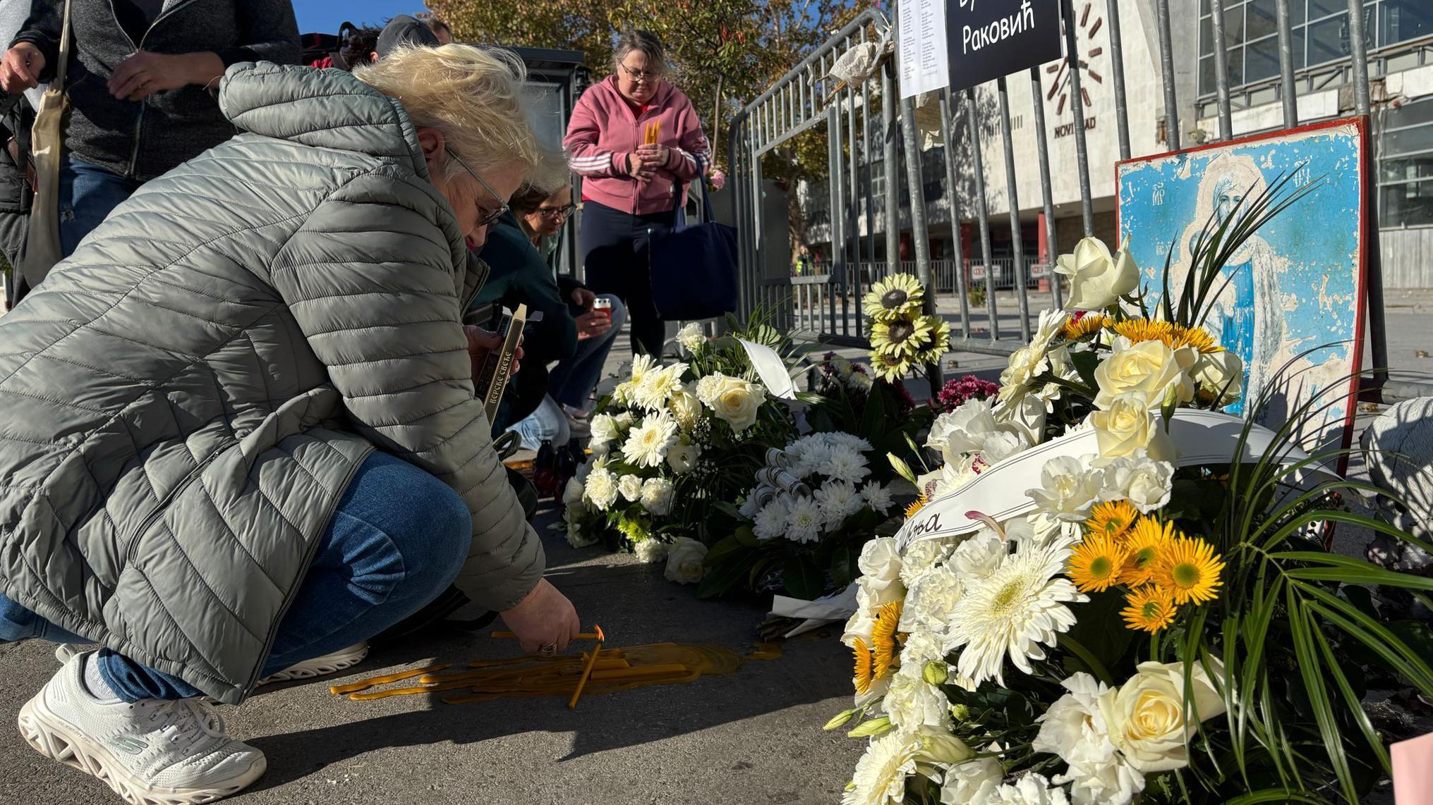 Žena pali sveće ispred železničke stanice u Novom Sadu