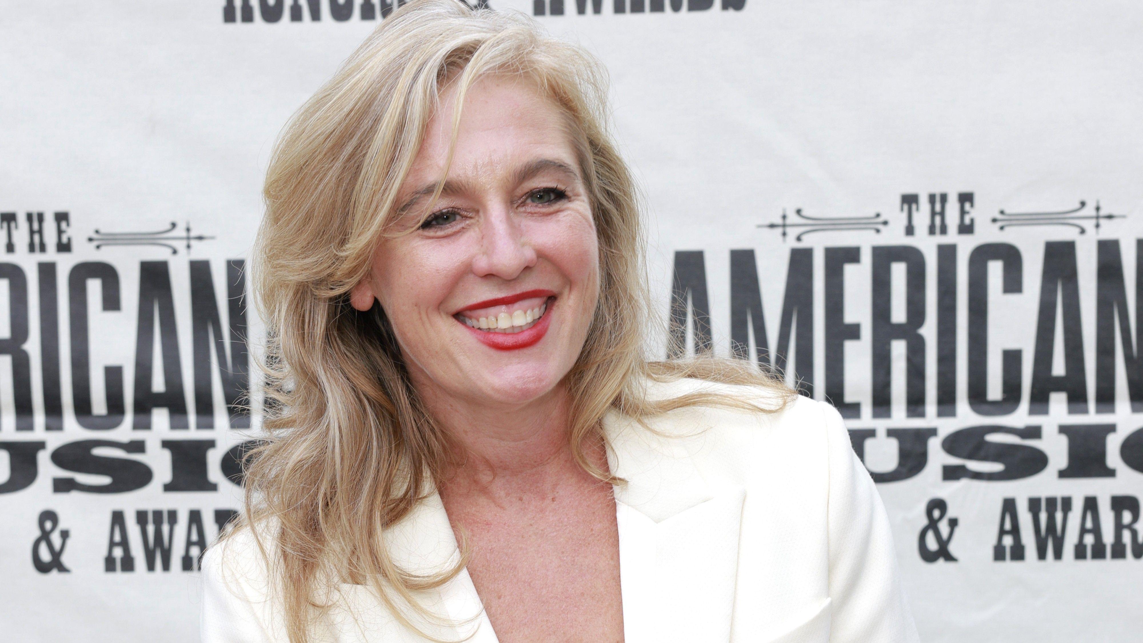 Tift Merritt no tapete vermelho de uma cerim&ocirc;nia de premia&ccedil;&atilde;o em Nashville, Tennessee. Sorrindo, com cabelo loiro, ela usa uma jaqueta branca.