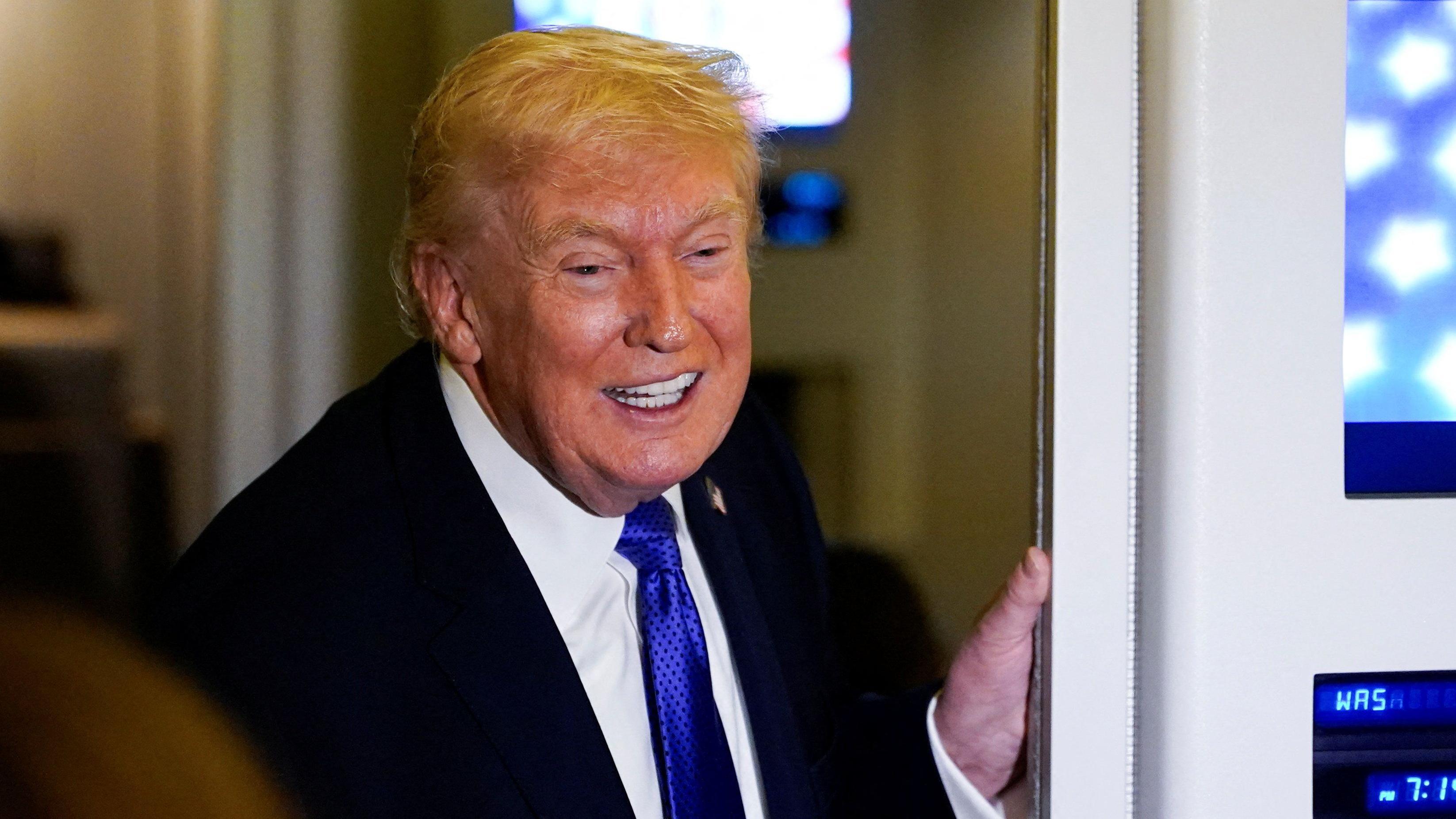 Un sonriente Donald Trump habla con periodistas a bordo del avión presidencial