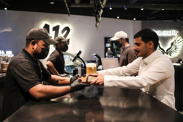A bartender serves non-alcoholic draft beer to a Saudi customer at the A12 cafe in the capital Riyadh on October 24, 2025. Draft beer, peanuts and big-screen sports... the scene is reminiscent of pubs worldwide, but in Riyadh customers in white robes or black veils sip non-alcoholic pints, with no expectation of a hangover.