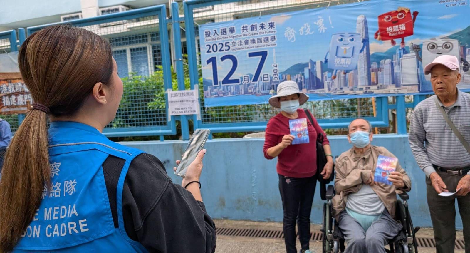 兩名長者手持政府送出的心意謝卡、另一名長者則站在票站外拍照留念。