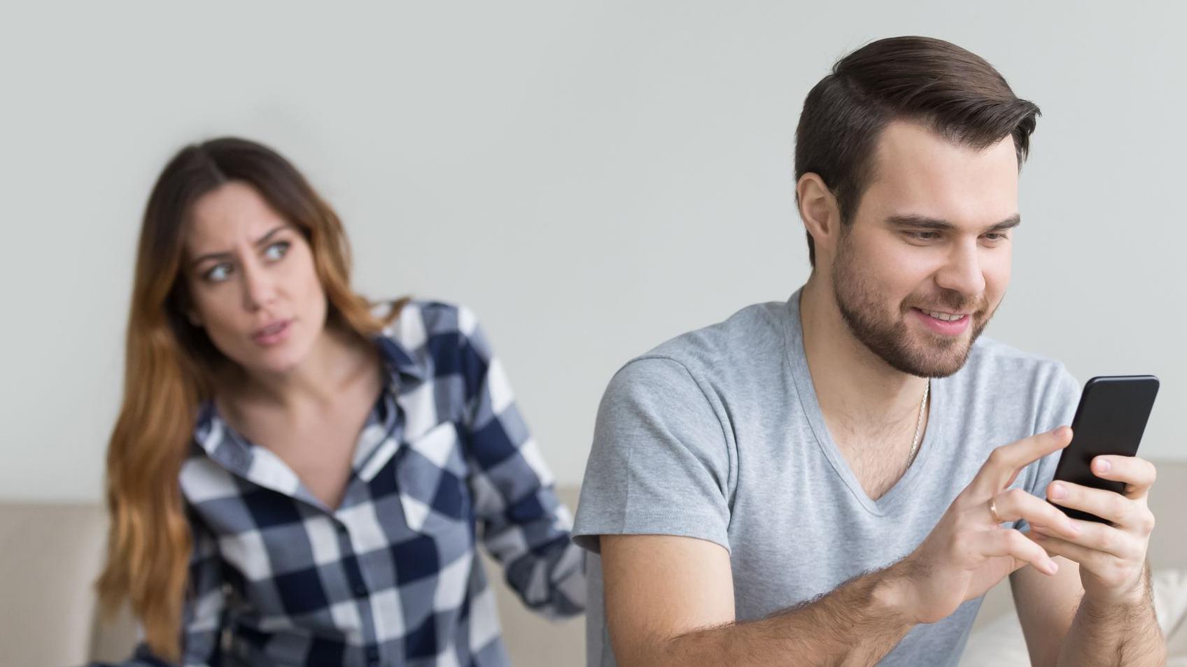 Esposa desconfiada discute com o marido que segura o celular. 