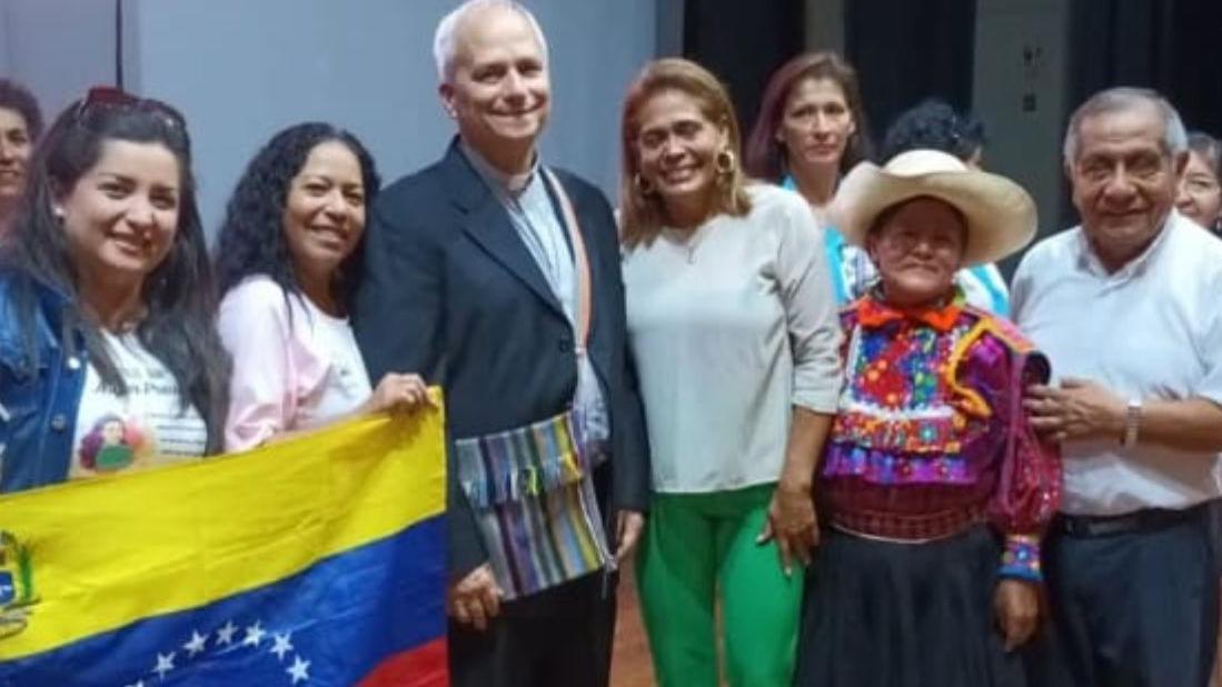 Lizbeth Díaz, junto al entonces obispor Robert Prevost y una bandera venezolana.