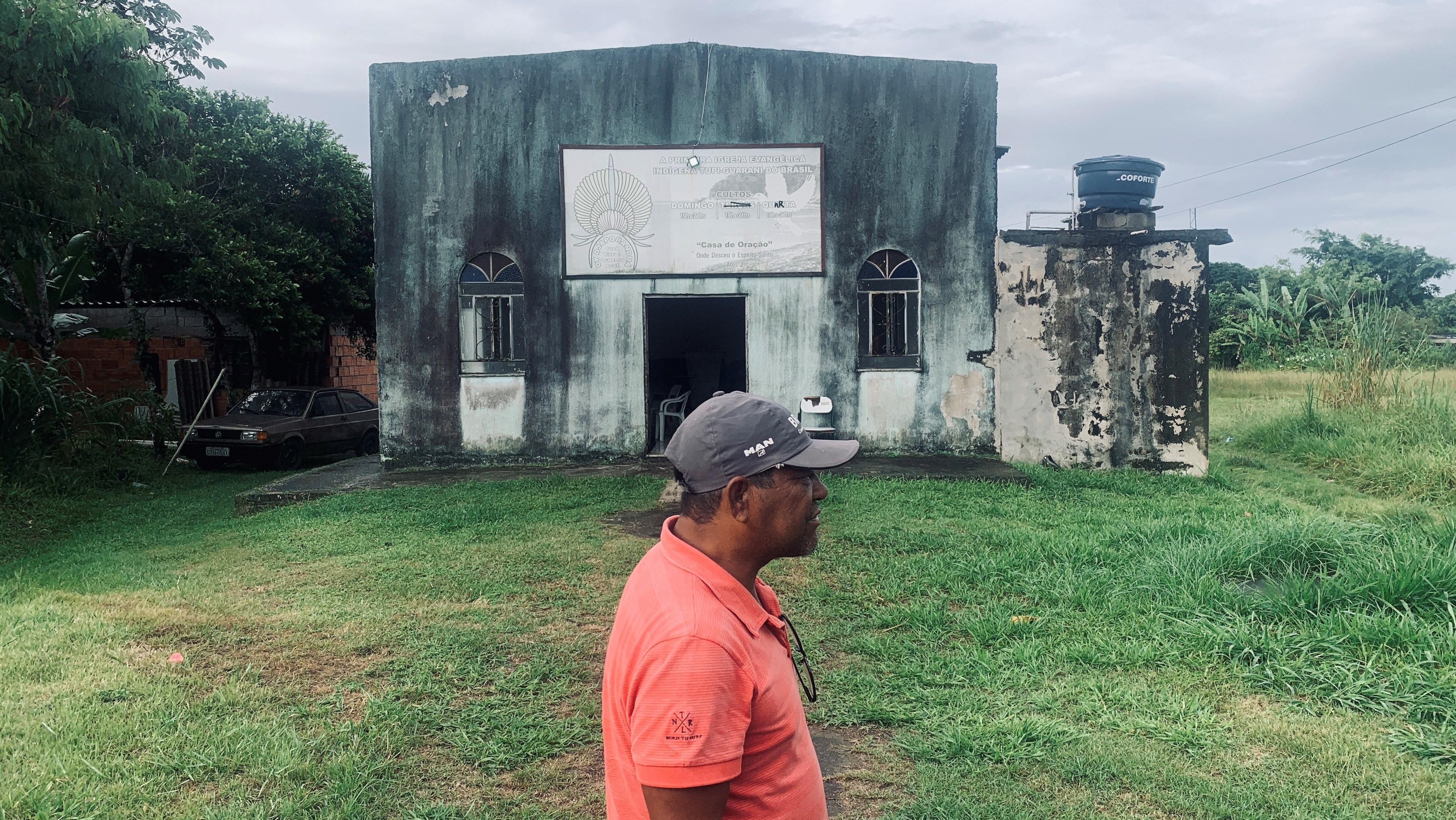 Um homem em frente a uma igreja em uma aldeia indígena