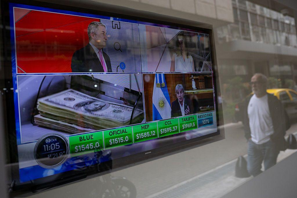 Un hombre pase cerca de un monitor que muestra la cotización del dólar en Argentina