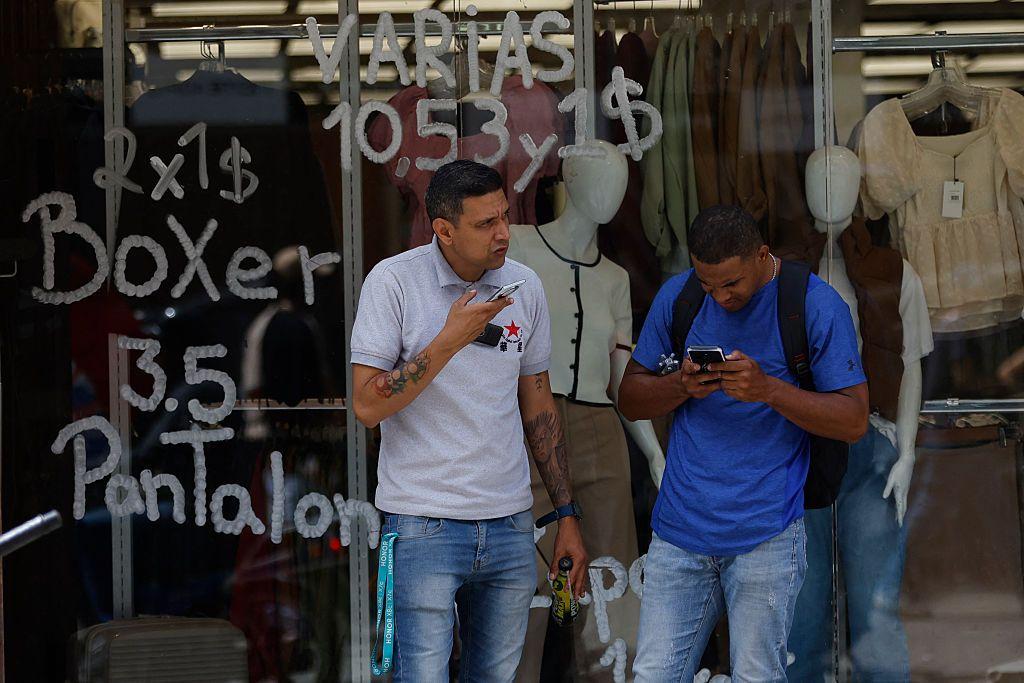 Personas frente a una tienda que exhibe precios en bolívares (moneda oficial venezolana) y dólares estadounidenses en Caracas, Venezuela, el 2 de junio de 2025.