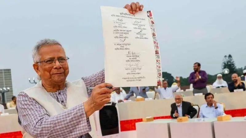 O l&iacute;der do governo interino, Muhammad Yunus, est&aacute; segurando a c&oacute;pia assinada da Declara&ccedil;&atilde;o Nacional de Julho de 2025