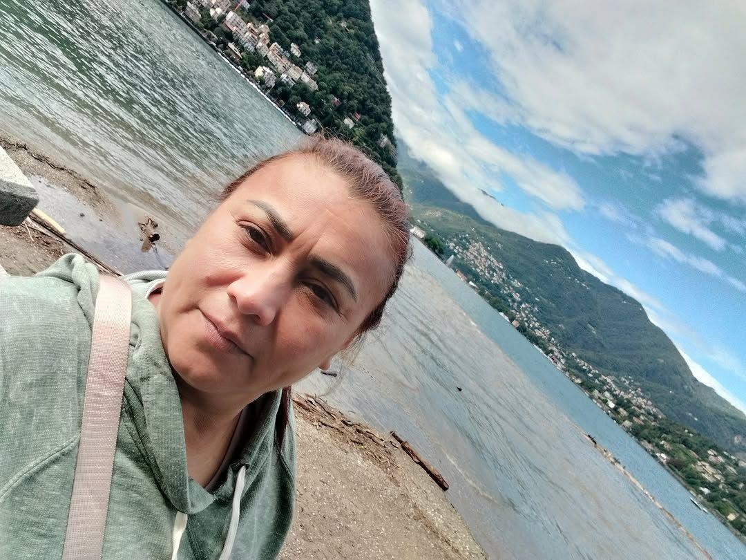 Yulixa con un saco verde al lado de un lago