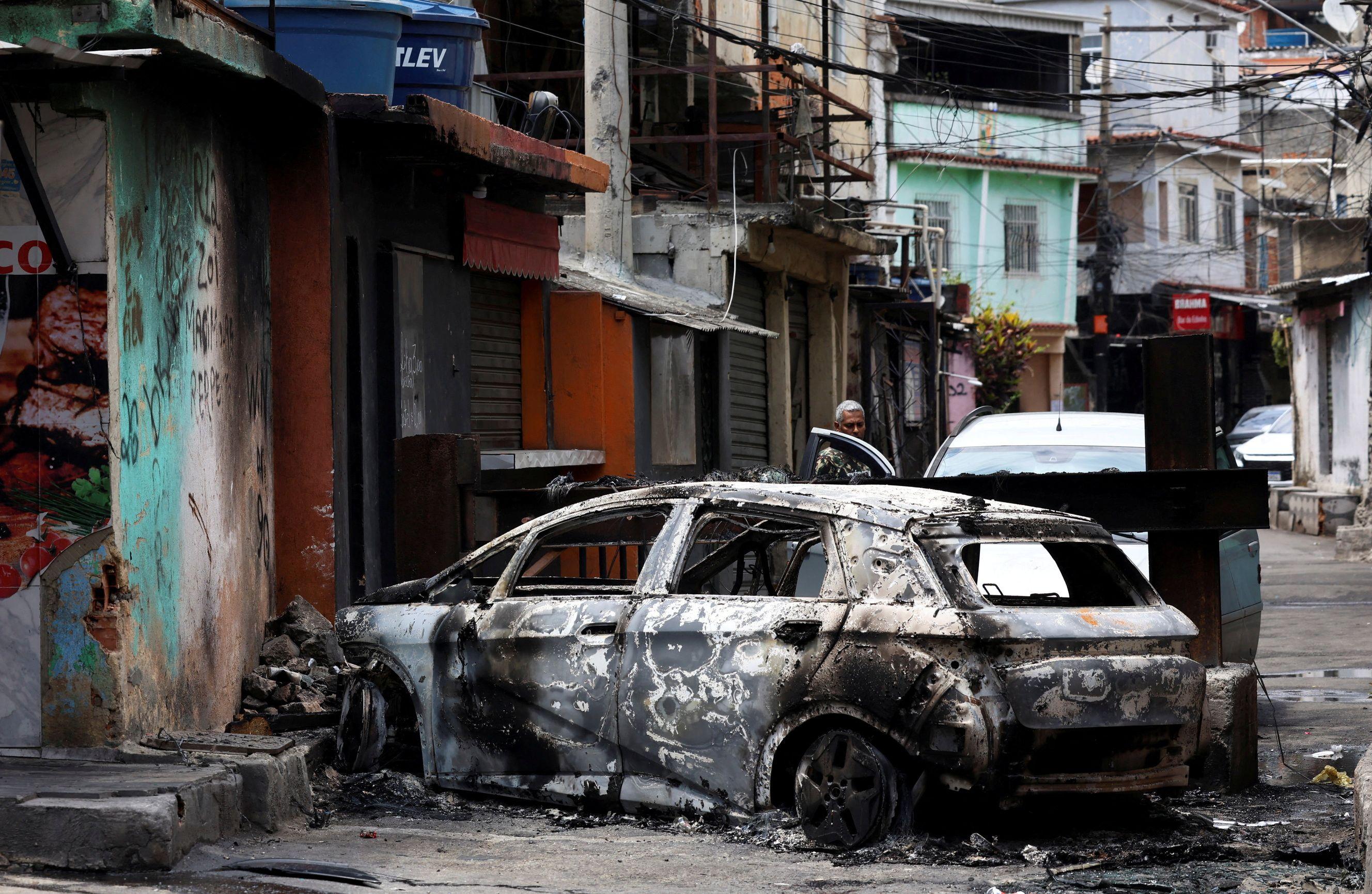 Una persona observa detrás de un auto quemado durante un operativo policial contra el narcotráfico en la favela do Penha, en Río de Janeiro, Brasil, el 28 de octubre de 2025.