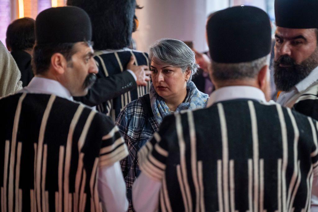 امرأة إيرانية تقف بجوار مجموعة من رجال البختياريين الرُحل أثناء زيارتها لمعرض السياحة الثامن عشر في مجمع المعارض الدولية في العاصمة الإيرانية طهران في 11 فبراير 2025