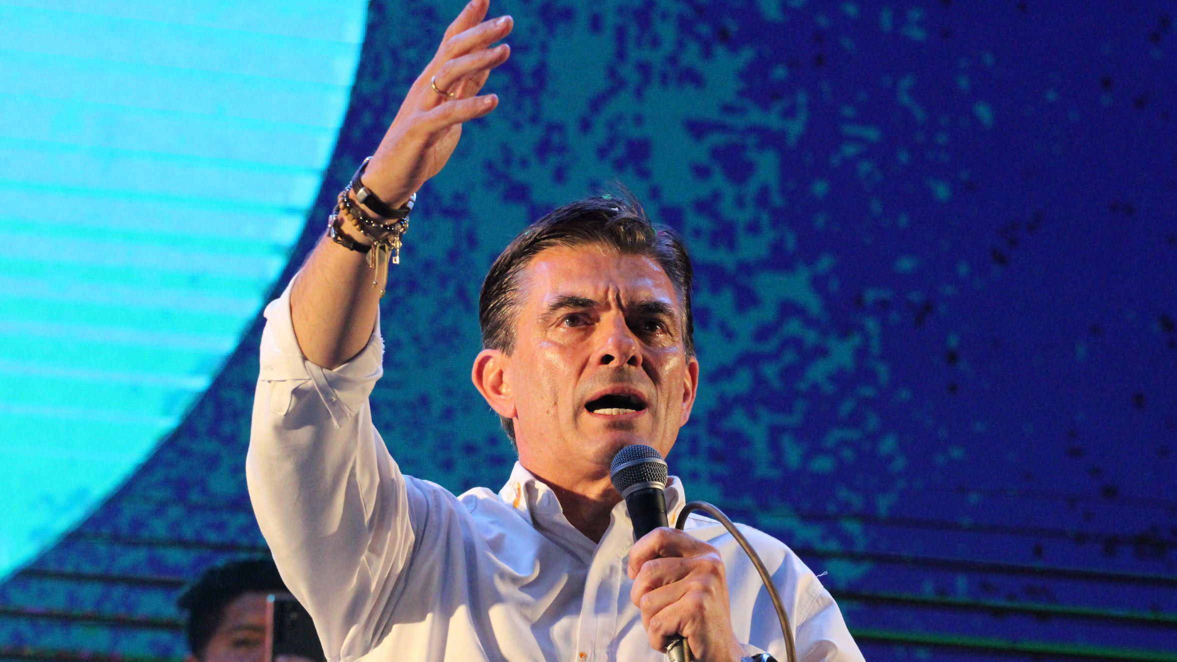 Rodrigo Paz con un micrófono en la mano y el otro brazo extendido