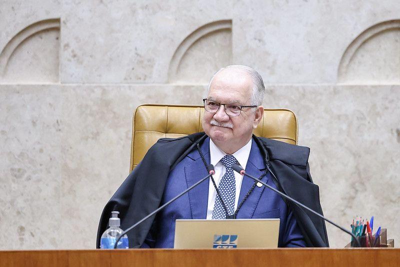 Fachin sentado na cadeira de presidente do STF, de terno azul e toga de juiz