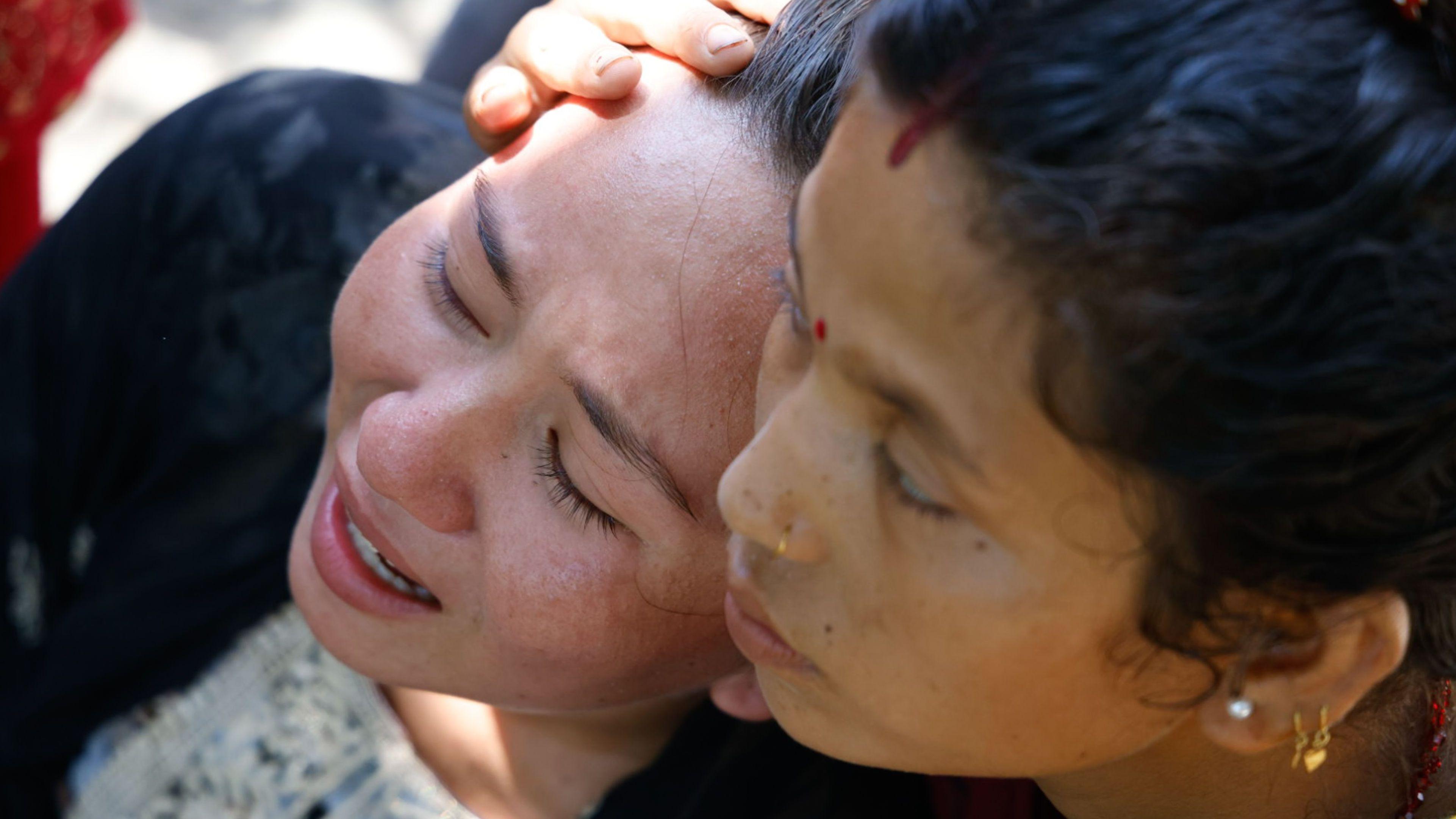 Una mujer llora, mientras otra la consuela en Nepal.