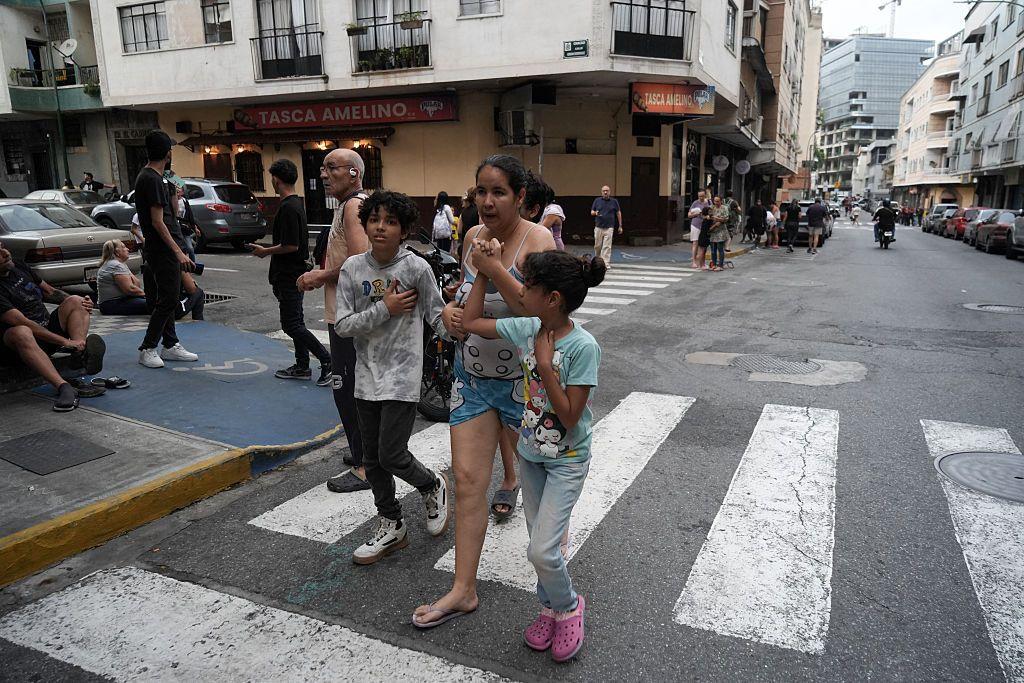 Una mujer camina por la calle con su hija e hijo cogidos de la mano, asustados después del terremoto.