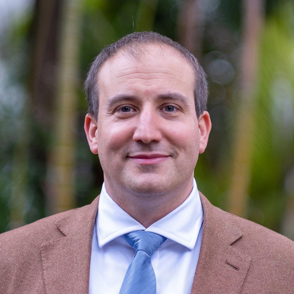 Retrato do professor Marko Milanovic, da Universidade de Reading (Reino Unido), com fundo desfocado. Ele usa terno e gravata e sorri com a boca fechada.