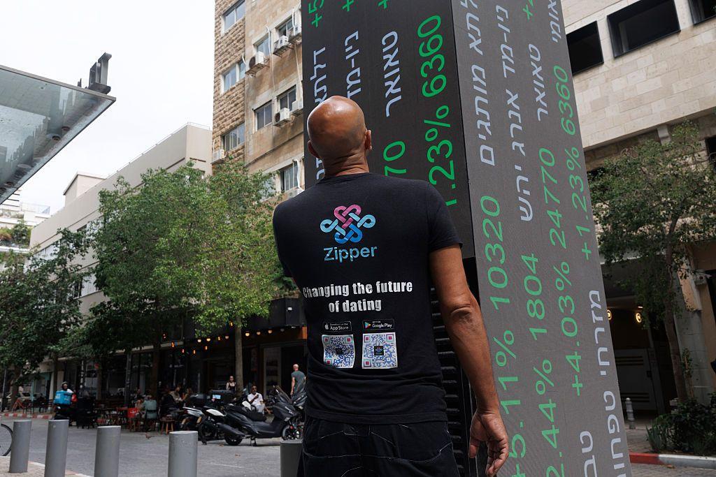 رجل يقف أمام أسعار الأسهم على لوحة إلكترونية خارج بورصة تل أبيب في إسرائيل، يوم الخميس 9 أكتوبر/تشرين الأول 2025.