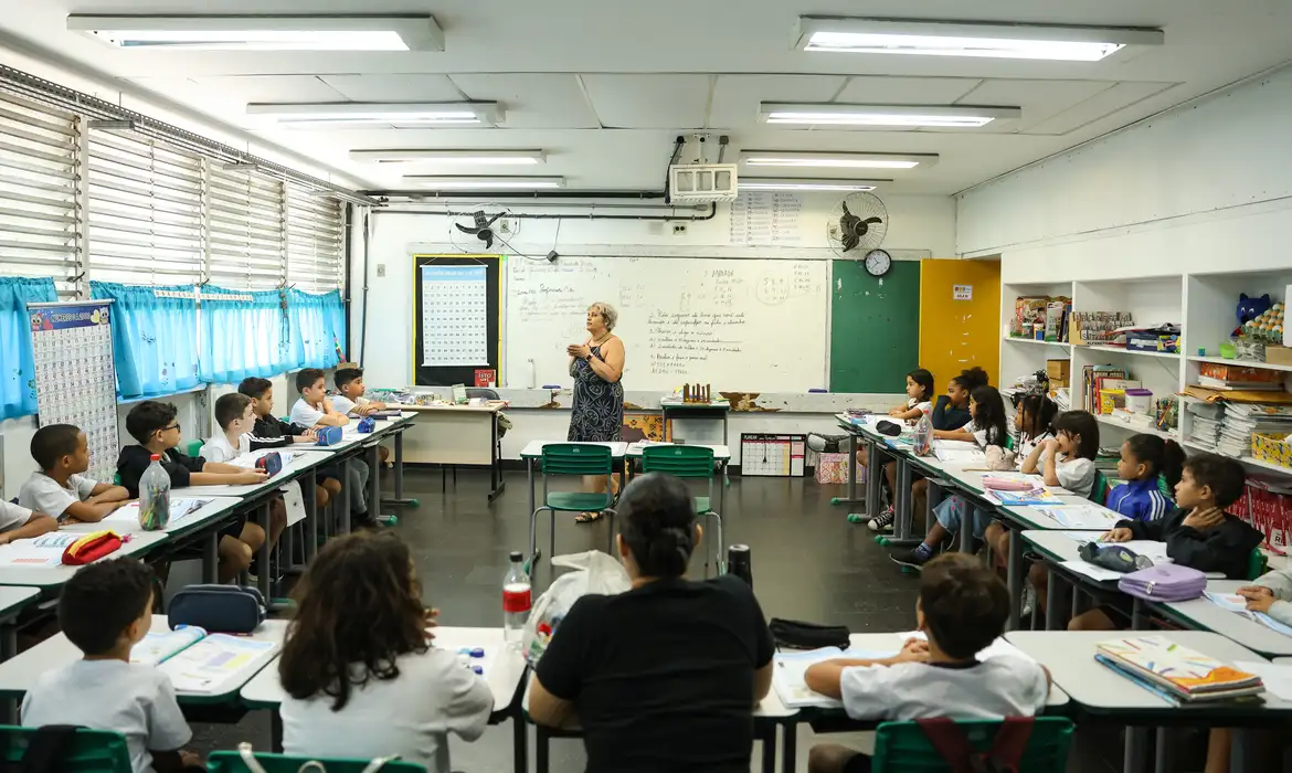 Alunos em sala de aula escutam professora