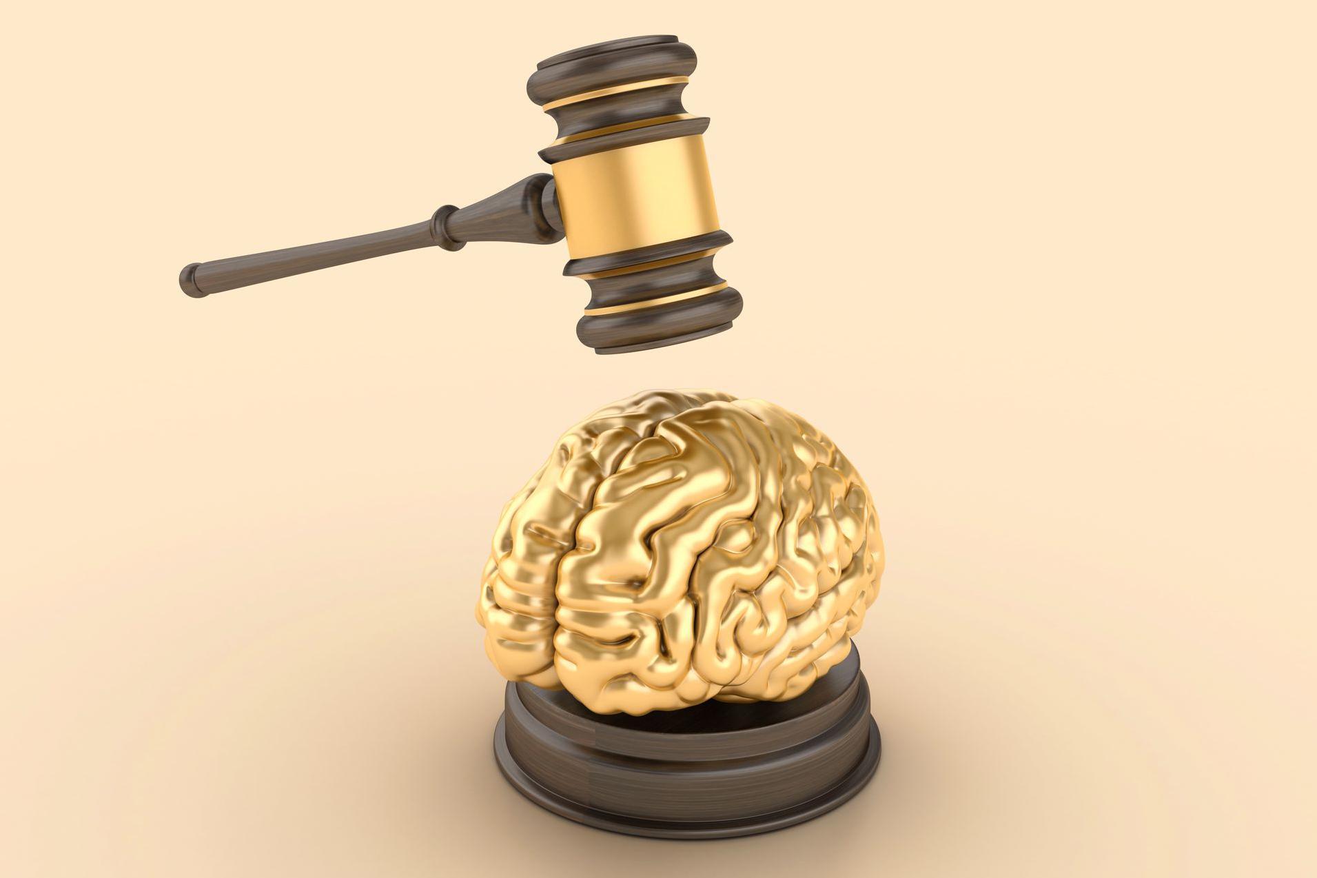 رسم ثلاثي الأبعاد يُظهر دماغاً ذهبي اللون موضوعاً على قاعدة خشبية تشبه تلك المستخدمة في قاعات المحاكم، وفوقه مطرقة قاضٍ خشبية تستعد للطرق عليه. الخلفية بلون بيج فاتح، مما يسلّط التركيز على العناصر الرئيسية.