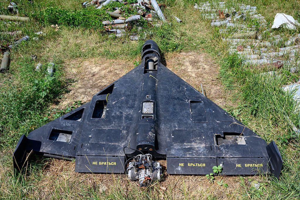 Un dron de color negro con escritura en ruso en las alas, yace derribado sobre césped.