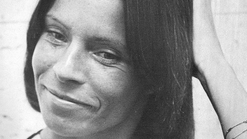 Una imagen en primer plano, en blanco y negro, de Kitty O'Neil sonriendo y apartando la mirada de la cámara.