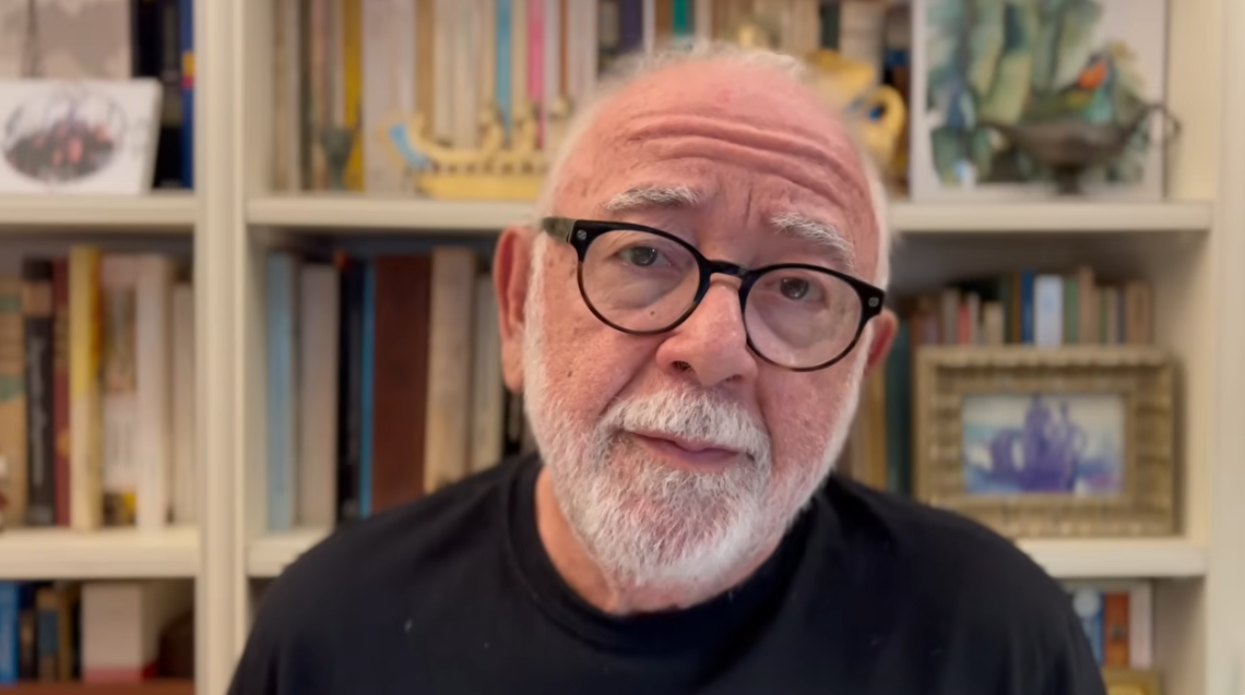 Cl&aacute;udio Moreno usando uma blusa preta e &oacute;culos com arma&ccedil;&atilde;o preta