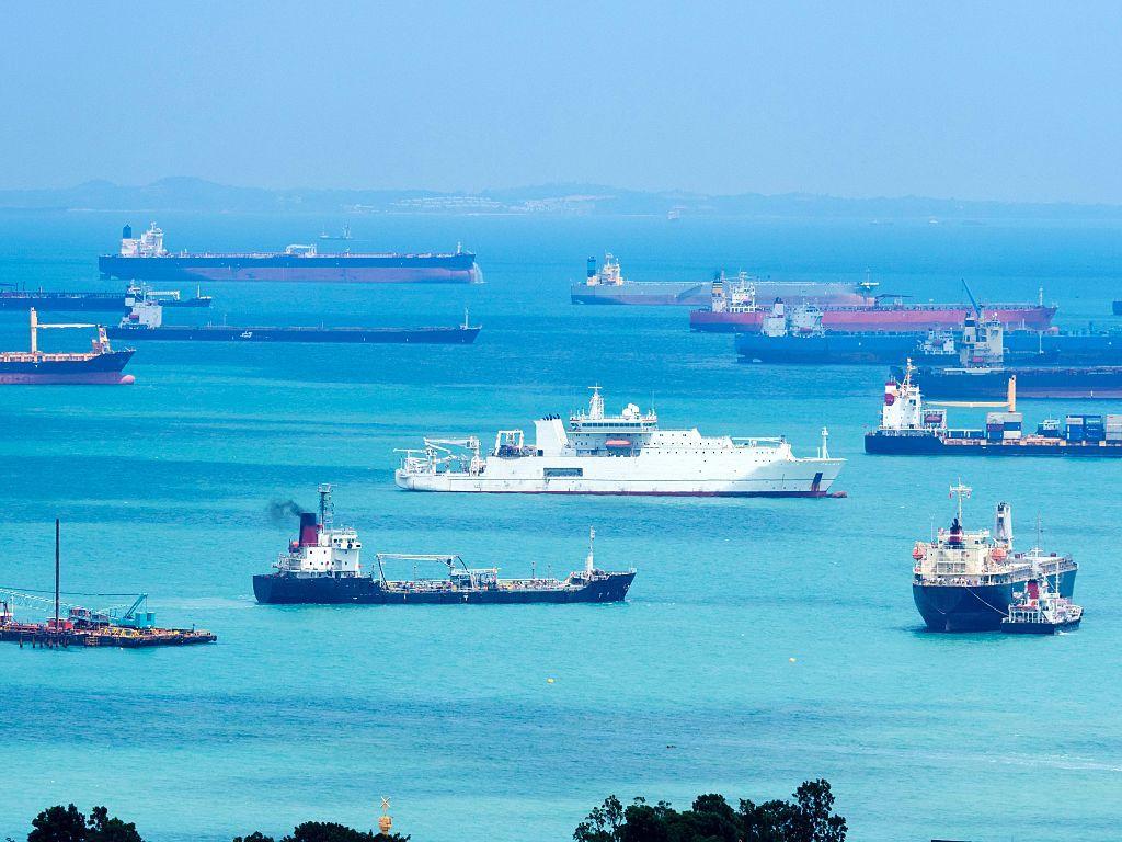 مجموعة من السفن والبواخر في مضيق ملقا في صورة التقطت نهاراً. المياه تبدو صافية والموج هادئ.