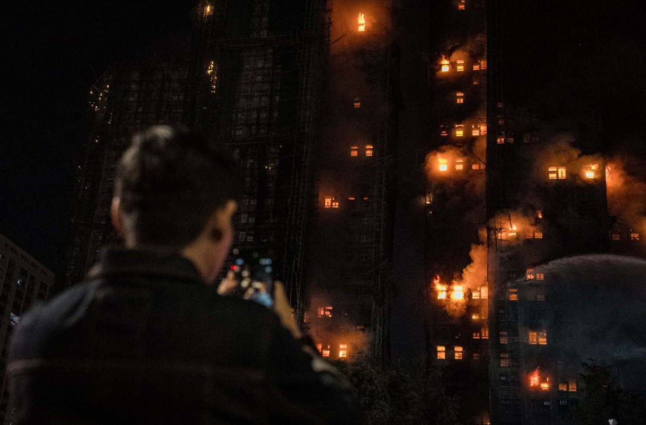 Un hombre mira un edificio consumido por las llamas en Hong Kong