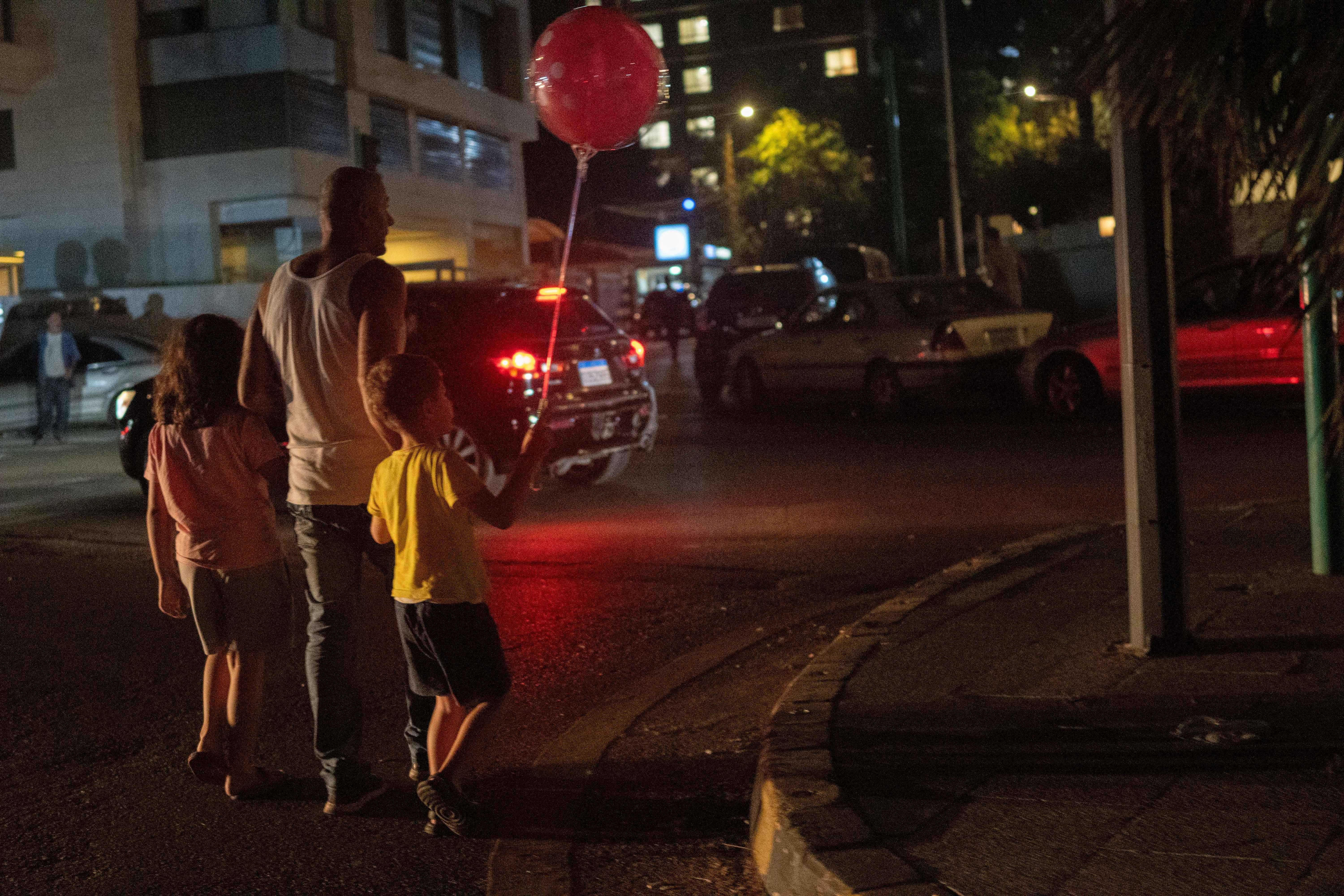 رجل يسير مع طفلين فيما يمكث نازحون لبنانيون ليلتهم في شوارع بيروت بعد فرارهم من الجنوب والضاحية الجنوبية باتجاه الشمال، وسط موجة نزوح جماعي.