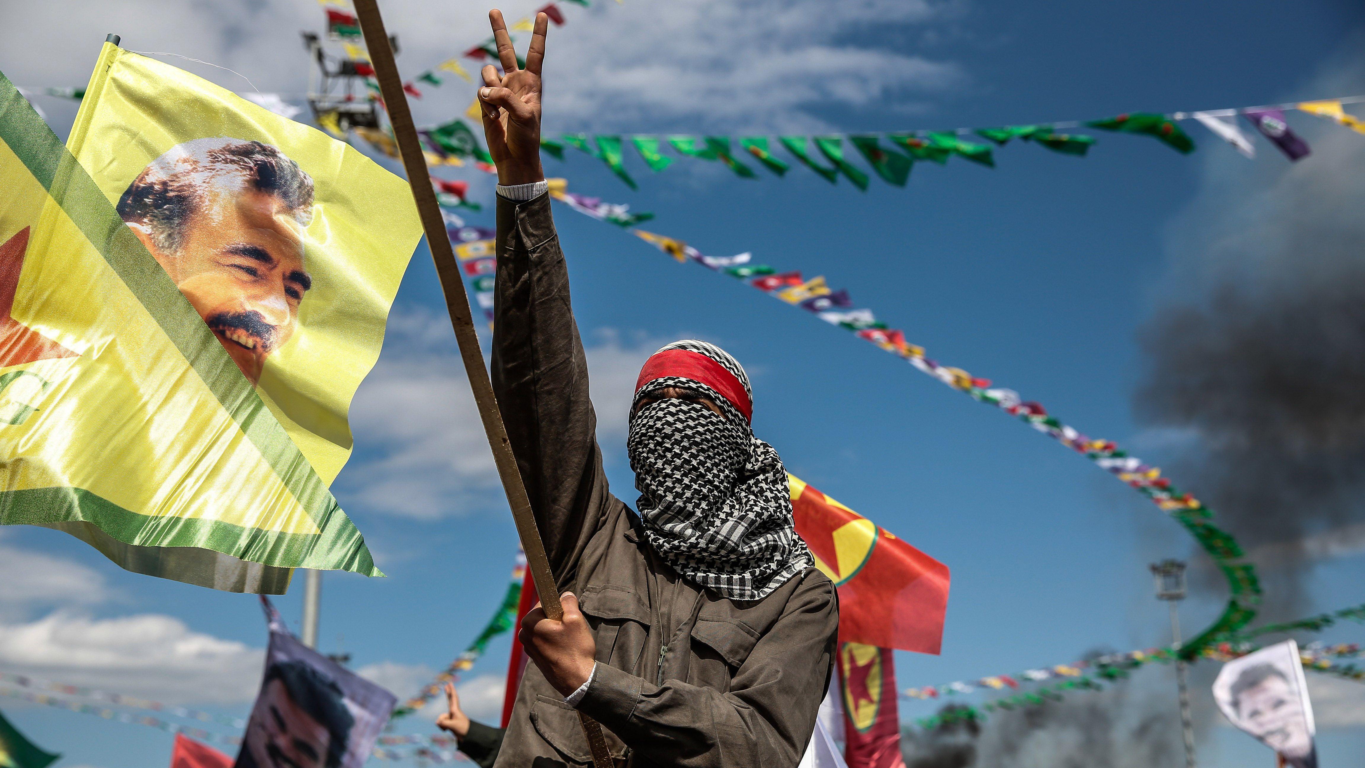 Un kurdo de Diyarbakir, en el sureste de Turquía, hace una señal de victoria. Junto a él, una bandera con la imagen del líder del PKK encarcelado, Abdullah Ocalan.