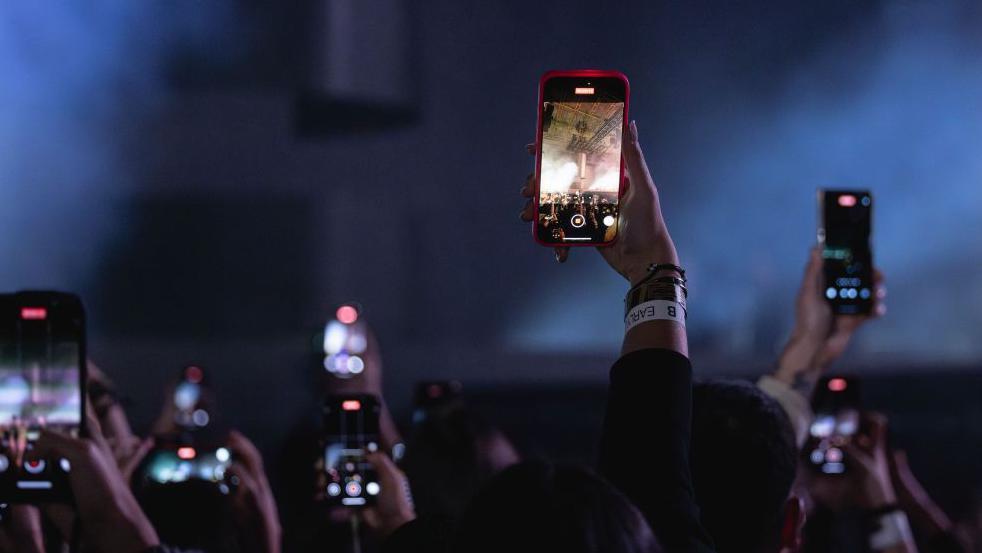 Vista del público tomando fotos con sus teléfonos móviles durante un concierto