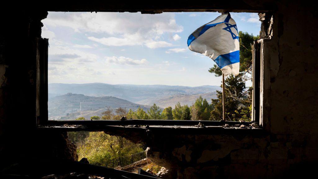Sebuah bendera Israel berkibar di jendela gedung yang rusak selama perang antara Israel dan Hezbollah di Kibbutz Menara, Israel utara, 28 November 2024.