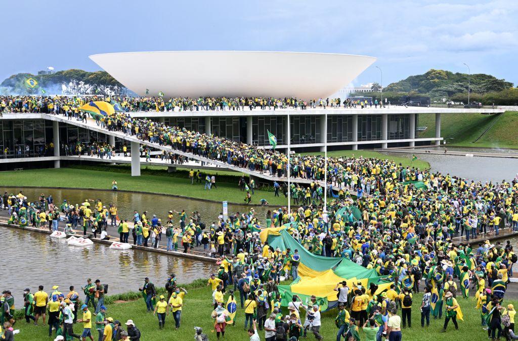 Una multitud de personas aglomeradas en torno a la Esplanada de los Ministerios en Brasilia. Algunos portan una bandera enorme de Brasil.