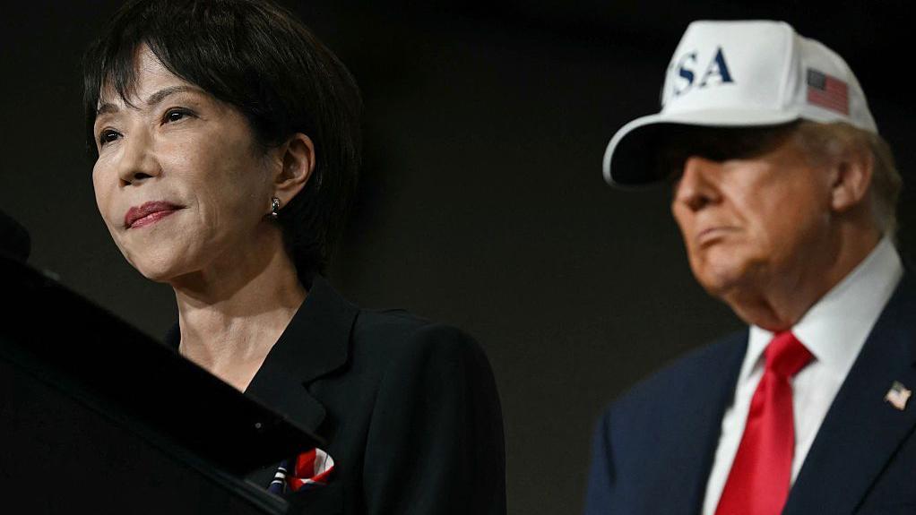S President Donald Trump (R) looks on as Japan's Prime Minister Sanae Takaichi speaks in front of US Navy personnel on board the US Navy's USS George Washington aircraft carrier at the US naval base in Yokosuka on October 28, 2025.