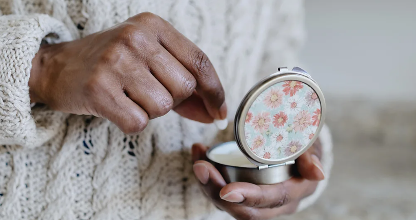 يد شخص يأخذ دواءً من علبة معدنية رُسمت عليها ورود حمراء وبيضاء