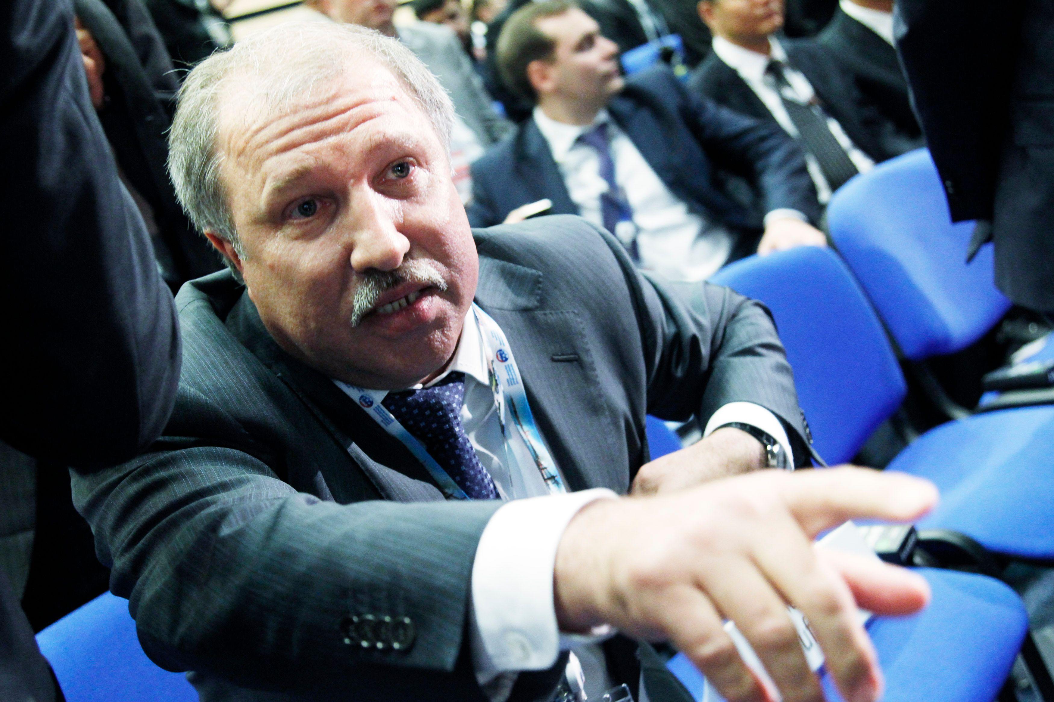 Eduard Hudainatov, predsednik naftne kompanije Rosnjeft, prisustvuje Međunarodnom ekonomskom forumu u Sankt Peterburgu (SPIEF) 17. juna 2011. godine. Pokazuje na nešto iza kamere dok sedi na plavim konferencijskim stolicama. Delimično je ćelav, ima sedu kosu i sede brkove i nosi sivo odelo. Ostali delegati sede iza njega.