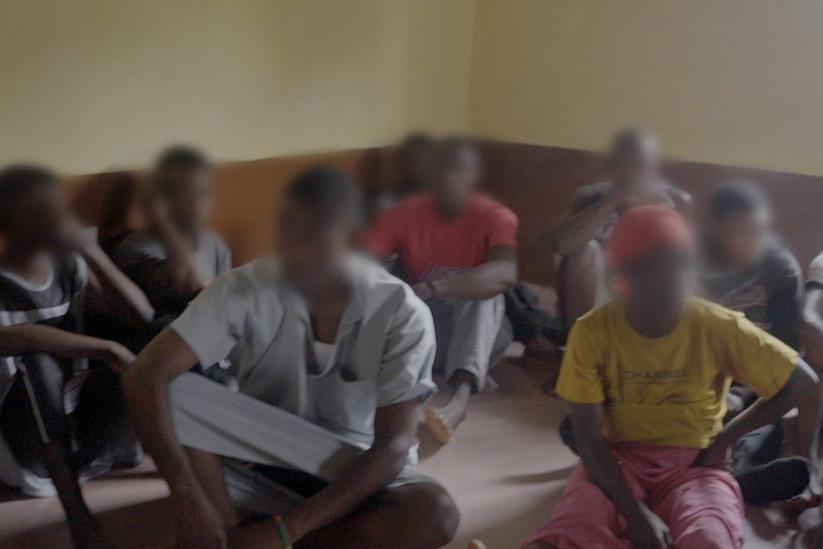 Jóvenes sentados en el suelo, con los rostros difuminados. Fueron encontrados en la casa que fue allanada por la policía en Makeni.