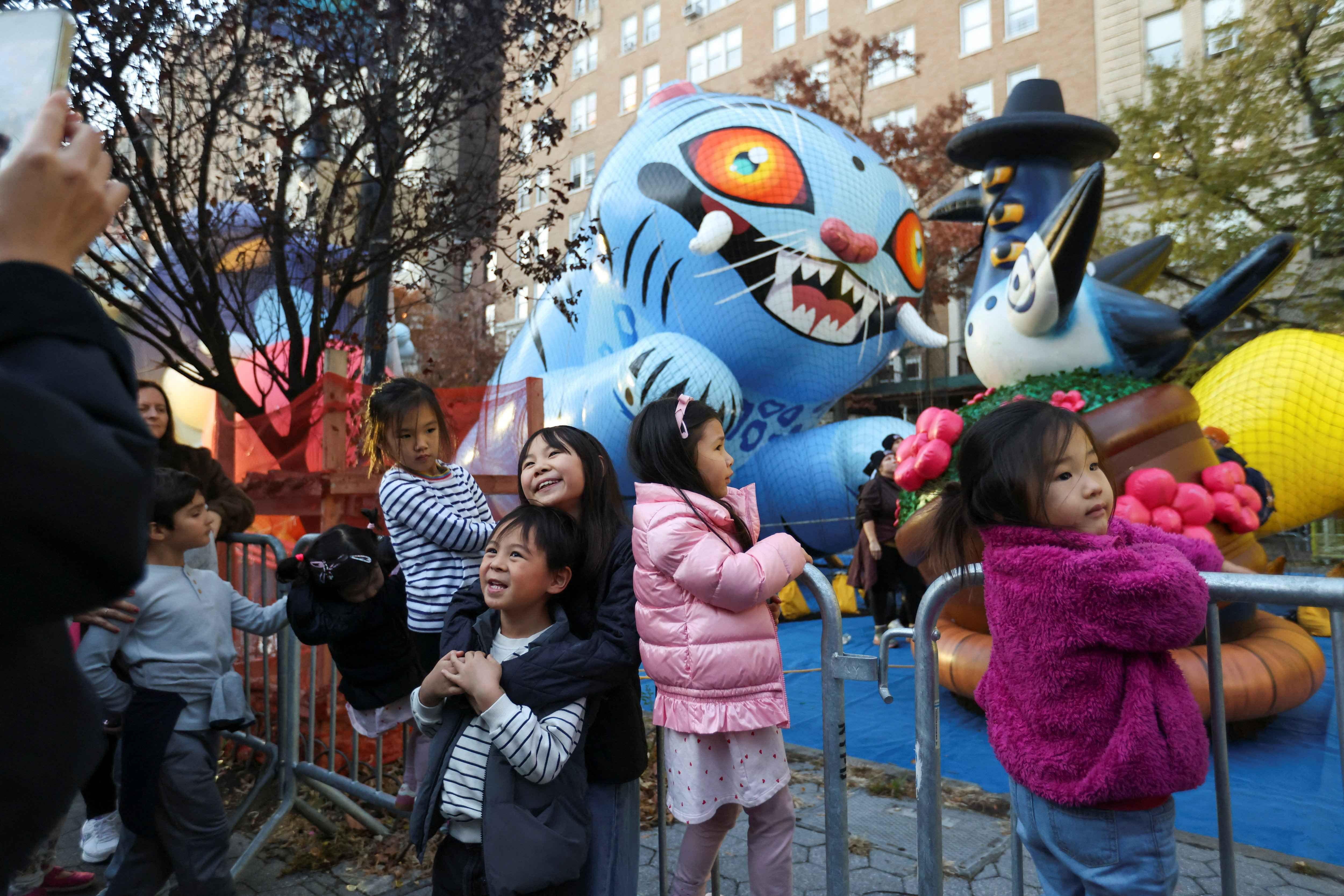 الأطفال يلتقطون صورة أمام بالون شخصية ديربي تايجر، عشية موكب عيد الشكر في الجانب الغربي العلوي من مانهاتن بمدينة نيويورك